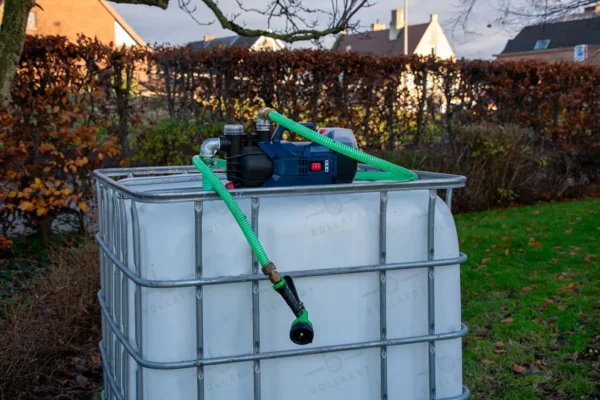 cuve-ibc-blanc-pompe-sur-batterie-1000L-nettoye-palette-acier-plastique-vue-de-gauche-environnement-du-jardin-avec-tuyau.webp